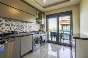 eine Küche mit Waschmaschine und Trockner und einen Balkon in der Unterkunft Flat w Shared Pool and Balcony 8 min to Beach in Belek