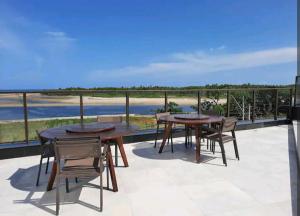 a patio with tables and chairs and a view of the ocean at Luxury Paiva Flat in Recife