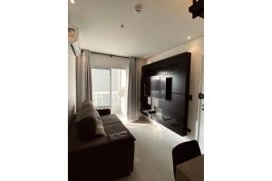 a living room with a couch and a flat screen tv at Apartamento Boqueirao Proximo a Praia, com Piscina in Praia Grande