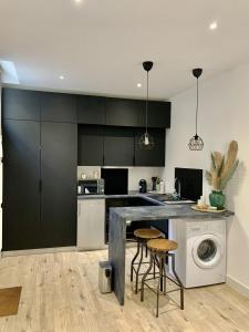 a kitchen with black and white cabinets and a washing machine at Trés jolie Studio Hyper Centre in Troyes