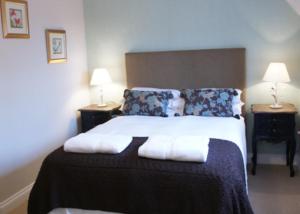 um quarto com uma cama grande, 2 mesas de cabeceira e 2 candeeiros. em The Bull at Great Totham Limited em Great Totham