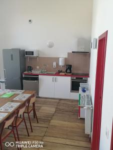 cocina con armarios blancos y suelo de madera en Gite d'Etape de Chirac, en Chirac