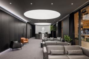 a lobby with couches and chairs and a large light fixture at Derand Hotel in Pristina