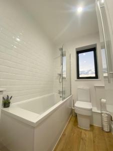 a white bathroom with a tub and a toilet at Stylish & Spacious Apartment in Royal Tunbridge Wells