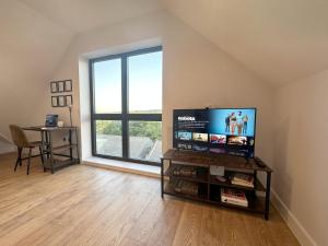 a living room with a flat screen tv and a window at Stylish & Spacious Apartment in Royal Tunbridge Wells