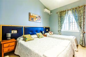 Dos camas en un dormitorio con paredes azules. en CASA RURAL VILLAMAYNO, en Alcaucín 70 fotos más