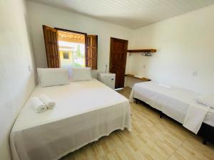 a bedroom with two beds and a window at Hospedaria Hibisco Xandó - Caraíva in Caraíva