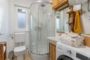 a bathroom with a shower and a washing machine at House Family Podhum in Dražice