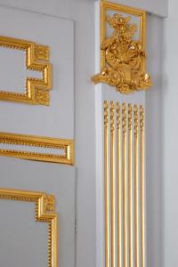 a row of gold frames on a white wall at Hotel Le Place d'Armes - Relais & Châteaux in Luxembourg