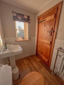 a bathroom with a sink and a wooden door at Sunny Dene Cottage in Knapton