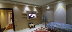 ein Schlafzimmer mit einem Bett und einem TV an der Wand in der Unterkunft Pyramids2 , Flat 309 ,2 Al Mansoureya Rd, Al Haram, Giza Governorate in Kairo