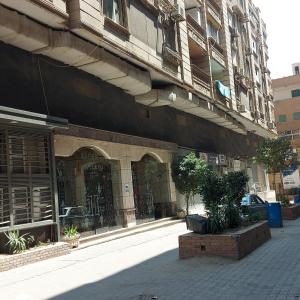 ein Gebäude auf einer Straße mit Pflanzen davor in der Unterkunft Pyramids2 , Flat 309 ,2 Al Mansoureya Rd, Al Haram, Giza Governorate in Kairo
