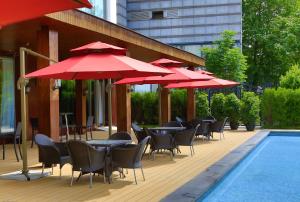 une rangée de tables et de chaises avec des parasols rouges à côté d'une piscine dans l'établissement Beijing Continental Grand Hotel, à Pékin