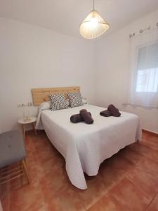 1 dormitorio con 1 cama blanca grande y 2 almohadas marrones en Piso Piteres 7 con piscina en Altea