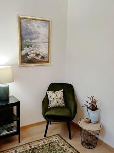 a green chair sitting in a living room with a painting at Dwór pod Sosnami Kaszuby in Ostrzyce