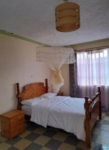 a bedroom with a bed with a wooden headboard and a window at Mfalme House, Ngoingwa Estate, 100 Metres from Thika-Mangu Rd, Close to Thika City Centre - Free Parking, Fast Wi-Fi, Smart TV, 2 Bedrooms Perfect for a Family of 2-4 Members in Thika