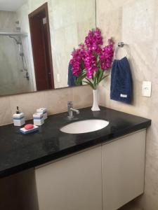 La salle de bains est pourvue d'un lavabo et d'un vase de fleurs roses. dans l'établissement Taiba Beach Resort Casa com piscina, à Taíba