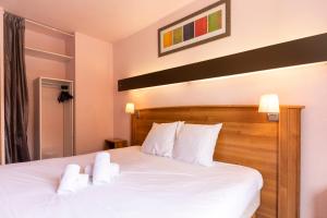 Schlafzimmer mit einem Bett mit weißer Bettwäsche und Kissen in der Unterkunft HOTEL DES NEIGES in Les Deux Alpes