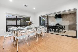 a dining room with a table and white chairs at Renmark River Villas and Boats & Bedzzz in Renmark