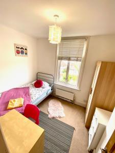 a bedroom with a bed and a table and a window at Palm House -Complete Holiday HOME IN SOUTHSEA in Portsmouth