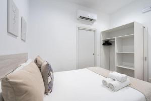 a white bedroom with a bed with towels on it at Apartamento acogedor y cómodo GUAD-C in Madrid