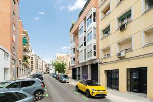 a yellow car parked on a street next to buildings at Apartamento acogedor y cómodo GUAD-C in Madrid
