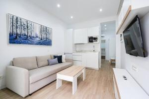 a white living room with a couch and a tv at Apartamento acogedor y cómodo GUAD-C in Madrid