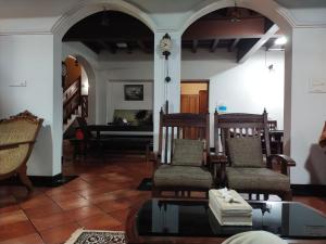 sala de estar con sillas, mesa y reloj en AZZA Heritage Home en Kochi