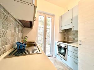 una cocina con armarios blancos y fregadero en Deliziosa villetta nuova vista lago, en Labro
