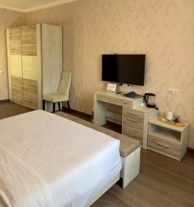 Schlafzimmer mit einem Bett und einem Schreibtisch mit einem TV in der Unterkunft Львівський in Lwiw