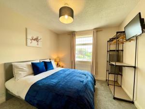 una camera da letto con un letto con lenzuola blu e una TV di Cosy Croft Cottage a Greasbrough