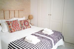ein weißes Bett mit einer schwarzen und weißen Decke und Kissen in der Unterkunft San Diego Cathedral Sevilla in Sevilla