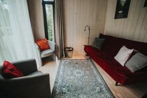 salon z czerwoną kanapą i 2 krzesłami w obiekcie Pine Nook w mieście Ogre