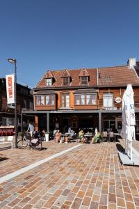 een groep mensen die rond een patio voor een gebouw zitten bij Hotel Brasserie De Beiaard in Torhout