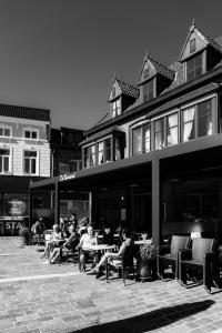 un grupo de personas sentadas en mesas fuera de un edificio en Hotel Brasserie De Beiaard, en Torhout