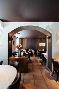 トルホウトにあるHotel Brasserie De Beiaardのテーブルと椅子、大きなアーチ道のあるレストラン
