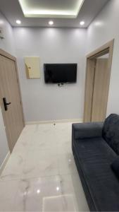 a living room with a couch and a tv on a wall at Manazel Al Faisal Furnished Apartments in Al Baha