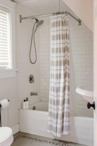 a bathroom with a bath tub and a shower curtain at The Beachside Burrow - Next to Sandbanks w Hot Tub in West Lake