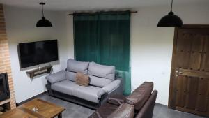 un salon avec un canapé et une télévision dans l'établissement casa de las Viñas 1 y 2, à Navaluenga