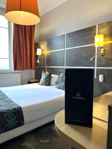 une chambre d'hôtel avec un lit et un ordinateur portable sur un bureau dans l'établissement Timhotel Boulogne Rives de Seine, à Boulogne-Billancourt