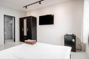 a bedroom with a bed and a tv on a wall at Breakers Hotel Rawai in Phuket