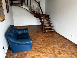 a living room with a blue chair and a staircase at Spacious, 3BD home in Radauti in Rădăuţi
