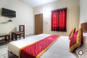 Schlafzimmer mit einem Bett, einem Schreibtisch und einem TV in der Unterkunft Coorg Avani Holiday Inn in Madikeri