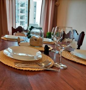 ein Holztisch mit Tellern und Weingläsern darauf in der Unterkunft ALTOS JUJUY ALQUILER TEMPORARIO in San Salvador de Jujuy