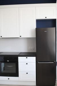 a kitchen with a black refrigerator and white cabinets at Authentic and Spacious flat in Jelenia Gora in Jelenia Góra