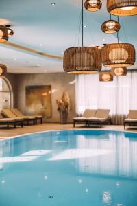 a large swimming pool in a hotel room with chandeliers at POST Family Resort in Unken