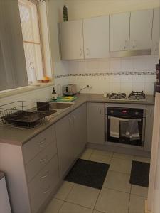 cocina con armarios blancos y fogones en South Hedland Accomodation - Nice - Tidy - Secure en South Hedland