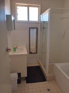 y baño blanco con lavabo y ducha. en South Hedland Accomodation - Nice - Tidy - Secure en South Hedland