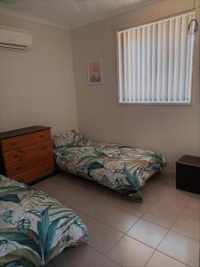 1 dormitorio con 2 camas, vestidor y ventana en South Hedland Accomodation - Nice - Tidy - Secure en South Hedland