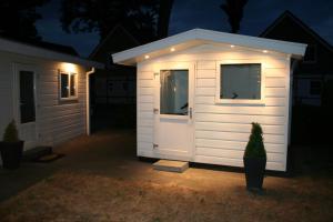 a white shed with a door in front of a house at Limburg-Chalet in Susteren